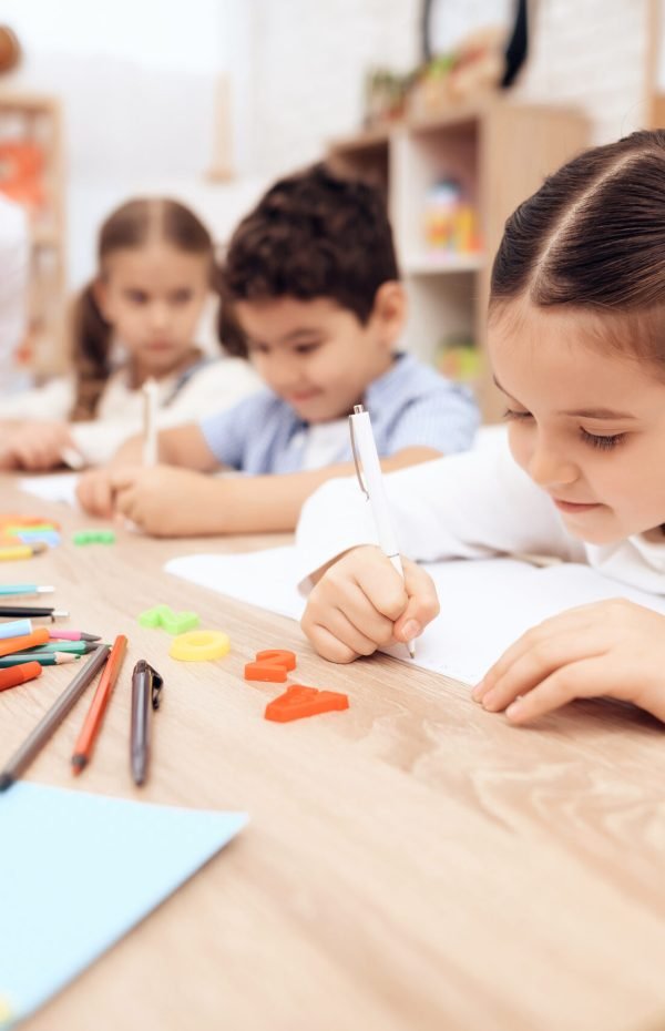 Children write in notebooks with a pen.